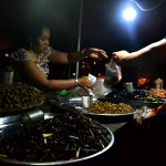 Vendor sells fried cricketss, grubs, water beetles and snails to a customer.